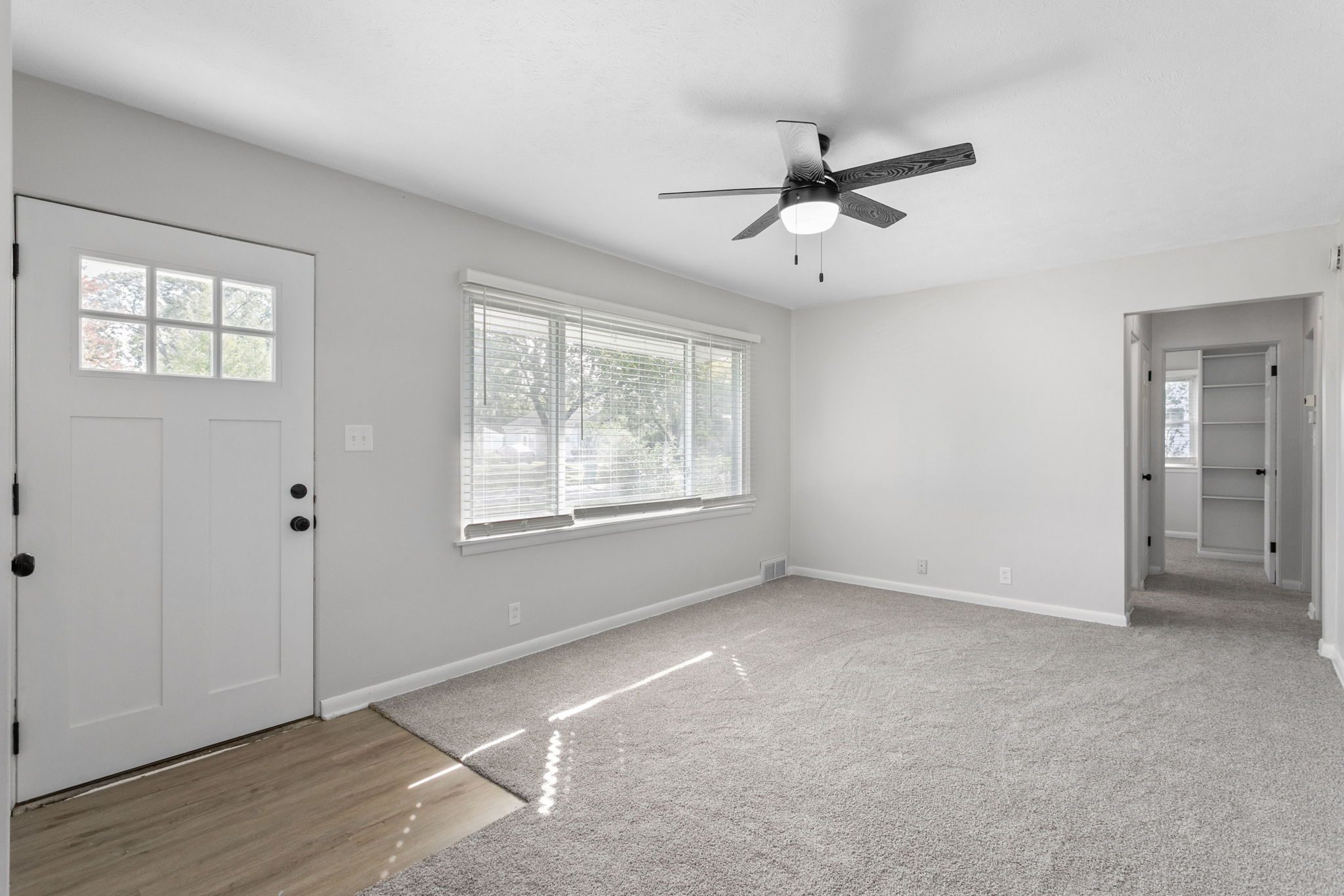 After: Living room with new carpet, front door, and neutral paint — 54611 28th St. South Bend
